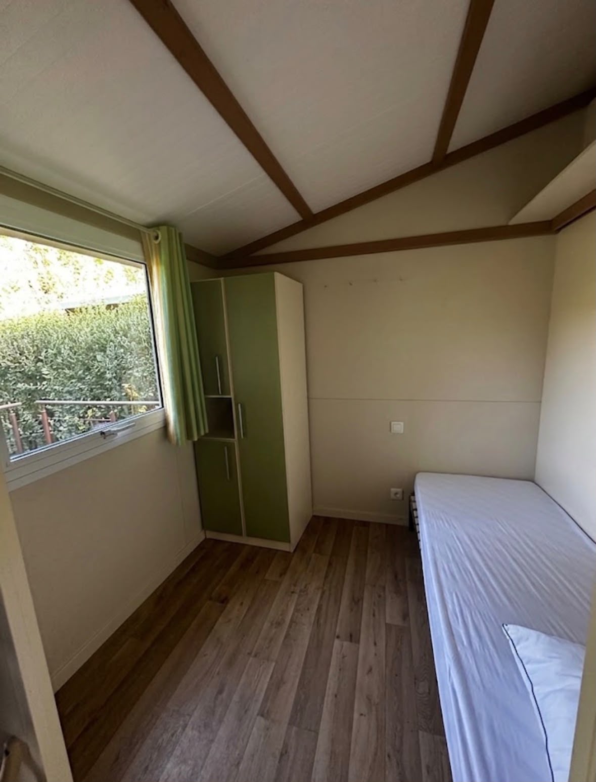 Chambre lumineuse avec armoire et vue sur la verdure